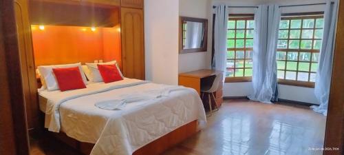 a bedroom with a bed with red pillows and a window at Pousada Viking Penedo in Penedo