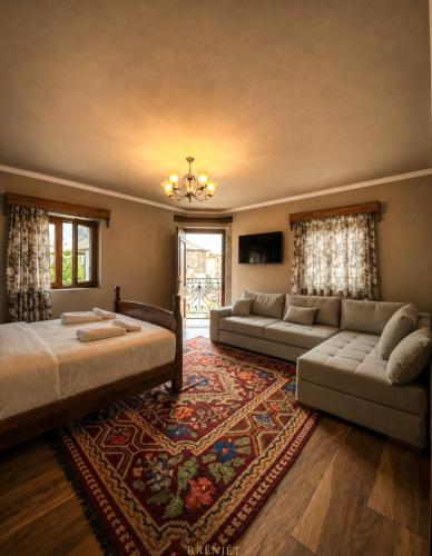 a bedroom with a bed and a couch and a rug at Rrenjet - The Roots in Ersekë