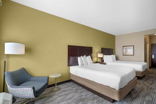 a hotel room with two beds and a chair at Best Western Plus Chalmette Hotel in Chalmette