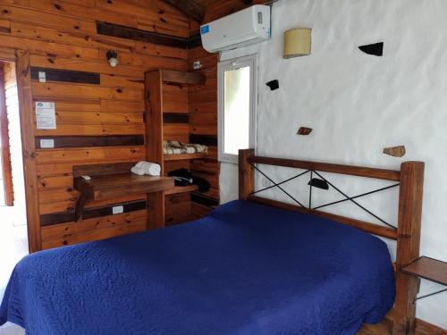 a bedroom with a blue bed in a wooden cabin at Posada La Solana in El Cadillal