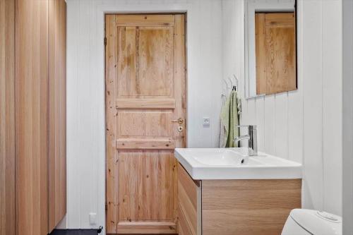a bathroom with a sink and a wooden door at LN1094-Hirtshals-Strandklitten-2 in Hirtshals