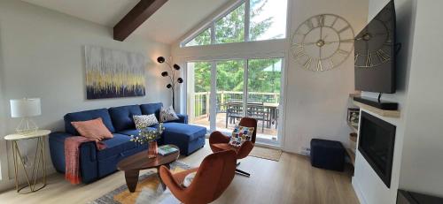 a living room with a blue couch and a clock at Kaïros - Private Spa & Golf Getaway in Saint-Basile