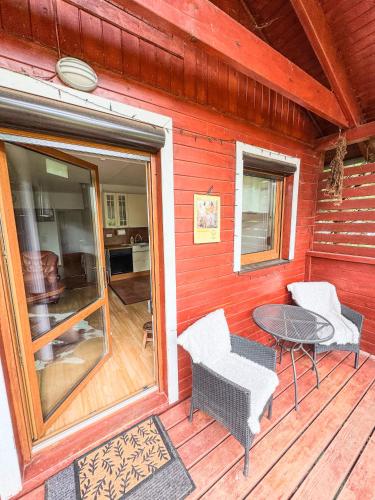a red house with a table and chairs on a porch at Domek v údolí in Božanov