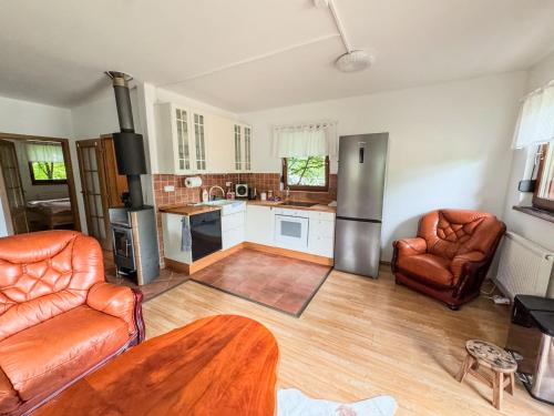 a living room with two leather chairs and a kitchen at Domek v údolí in Božanov