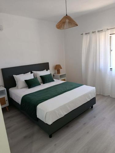 a bedroom with a large bed with a green blanket at Casa 56 in Sardoal