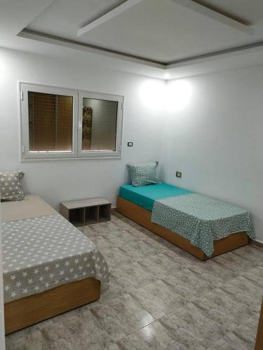 two beds in a room with two windows at Golden plage in Kelibia