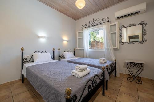 two beds in a bedroom with a mirror and a window at Villa Helona in Keri