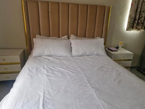 a bedroom with a large bed with white sheets and pillows at Cosy Corner Villa in Lusaka