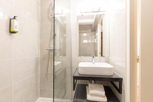 a bathroom with a sink and a shower at TheOriginals City, Hôtel restaurant l'Ormichal Dijon Sud in Marsannay-la-Côte