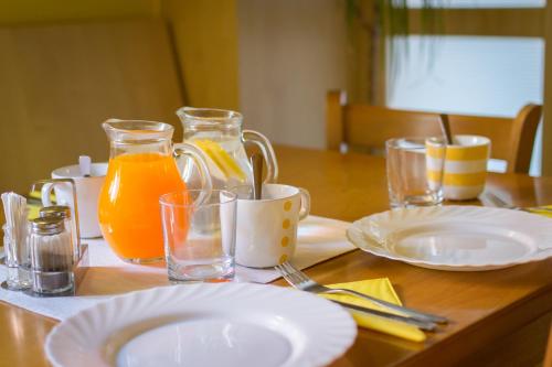 een houten tafel met borden en glazen sinaasappelsap bij Penzion V Koutě in Zlechov
