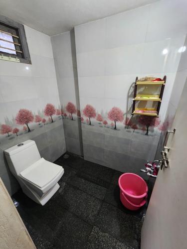 a bathroom with a toilet and a pink bucket at Shrunga Shreni Homestay - Near Bandaje trek and falls in Kalasa