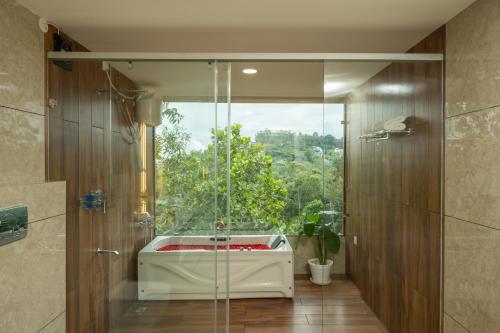 a bathroom with a glass shower with a tub at Misty Lake Resorts Munnar By Sylora Hotels in Munnar