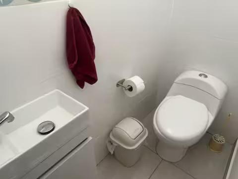 a white bathroom with a toilet and a sink at Ohana's Beach House in Punta Negra