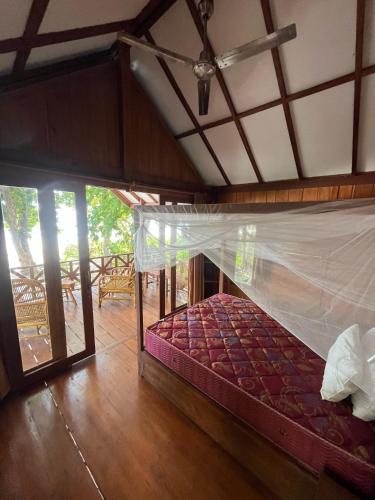 a bedroom with a bed with a mosquito net at SELAYAR TURTLE BAY in Barangbarang