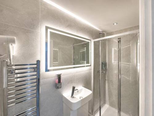 a bathroom with a sink and a shower at The Broadway Hotel - London Heathrow in Southall