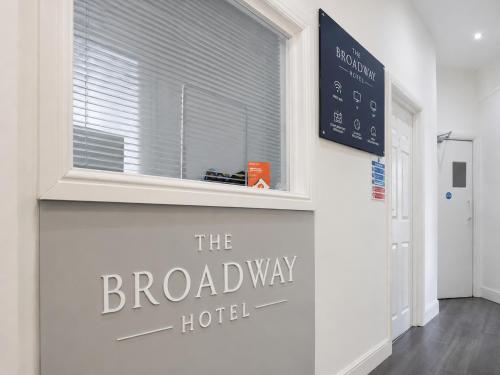 a sign for the broadway hotel on a wall with a window at The Broadway Hotel - London Heathrow in Southall