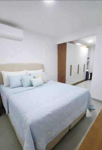 a bedroom with a large bed with blue pillows at Apartamento Confortável na Praia do Morro in Guarapari