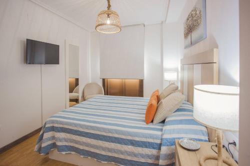 a bedroom with a bed with a blue and white striped blanket at Castillo Buenavista in Ponferrada