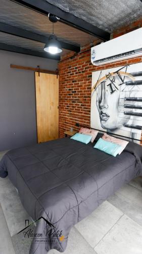 a large bed in a room with a brick wall at Loft Estilo Industrial in Ezeiza