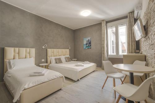 a bedroom with two beds and a table and chairs at Trieste Centro Rooms-camere eleganti in pieno centro in Trieste