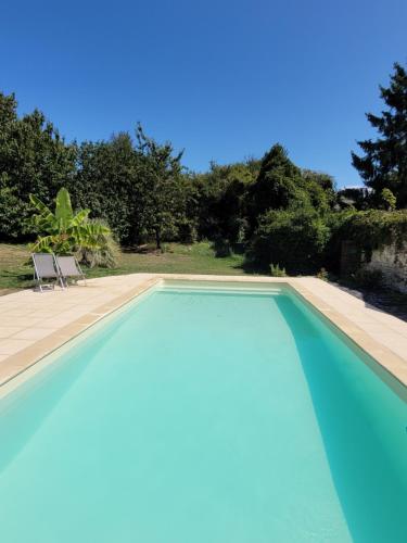 a blue swimming pool with two chairs and trees at Tente Lima in Ambillou-Château
