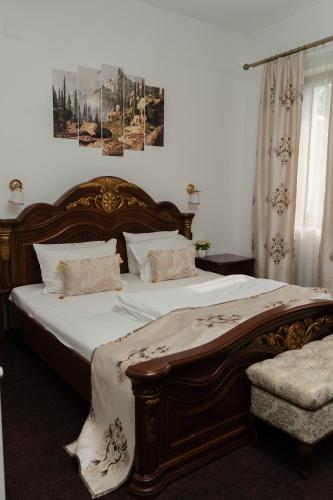 a bedroom with a large wooden bed with white sheets at VILA Corviniana in Hunedoara