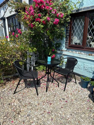 two chairs and a table in front of a house with roses at Turning Tides Holiday Cottage in Great Yarmouth