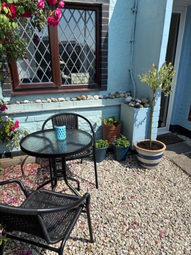 a patio with a table and chairs and potted plants at Turning Tides Holiday Cottage in Great Yarmouth
