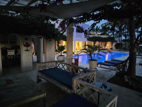 a patio with a bed and a pool at night at The Villa Luxury Suites Hotel in Diani Beach