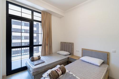 two beds in a room with a large window at Stylish 2BR Apartment in Yerevan in Yerevan