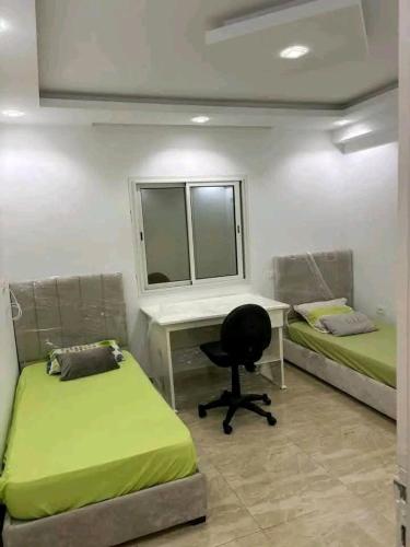 a bedroom with two beds and a desk and a chair at Residence Dorra in Monastir