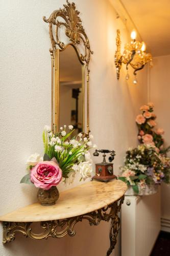 a table with a mirror and flowers on it at VILA Corviniana in Hunedoara