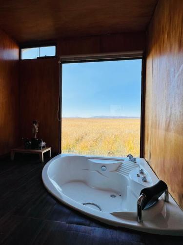 a bath tub in a room with a large window at Titikala in Puno