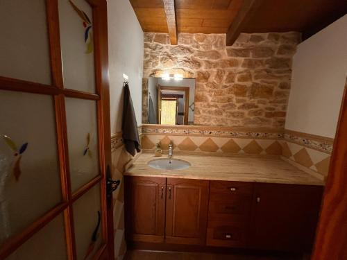 a bathroom with a sink and a stone wall at Casa Menta in Pomar de Valdivia