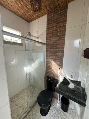 a bathroom with a black toilet and a glass shower at Casa do Pedrão in Eunápolis