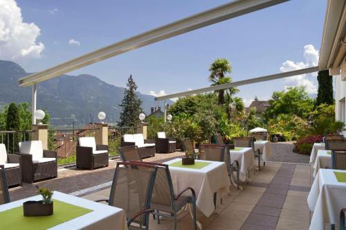 a restaurant with white tables and chairs on a patio at Hotel Sonnenhof in Marlengo