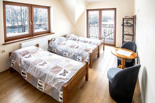 a room with two beds and a chair and windows at Pokoje nad Dunajcem in Biały Dunajec