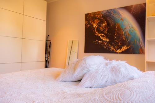a bed with a white comforter and a painting at Bright Apartment in Haapsalu in Haapsalu