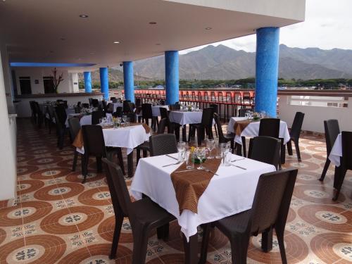 a restaurant with tables and chairs and mountains in the background at Hotel Oasys Blue in Roldanillo