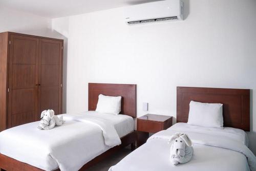 a bedroom with two beds with stuffed animals on them at Hotel Boutique Mura in Cancún