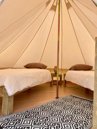 a canvas tent with two beds and a rug at Tente Inca in Ambillou-Château