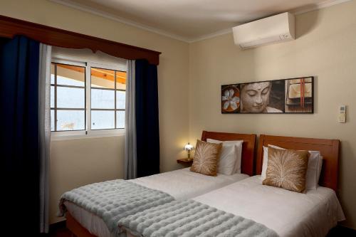a bedroom with two beds and a window at Paradise House Calheta in Calheta