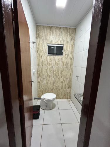 a bathroom with a toilet and a tv on the wall at Lar doce lar in Barra do Garças