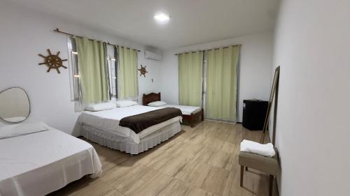 a hotel room with two beds and a chair at Pousada Holy Salt Cumbuco in Caucaia