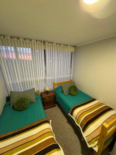 two beds sitting in a room with a window at Acogedor apartamento in Quilpué