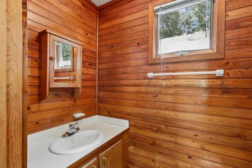 a bathroom with wooden walls and a sink and a window at The Tree House in Duck