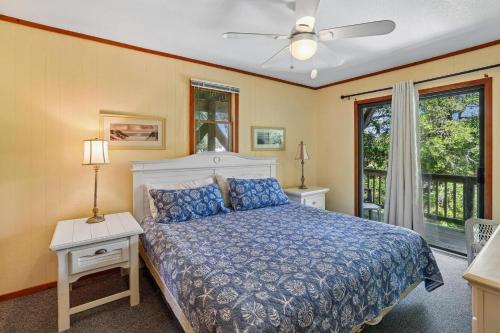 a bedroom with a bed with a blue comforter and a window at The Tree House in Duck