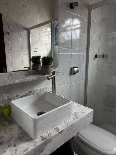 a white bathroom with a sink and a toilet at Casa de Praia com Piscina e Espaço Gourmet in Bertioga