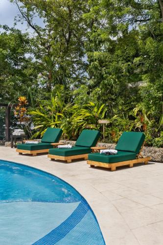 a row of green lounge chairs next to a swimming pool at Bolontiku Boutique Hotel Member of the Cayuga Collection in Flores