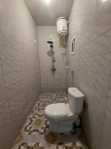 a bathroom with a white toilet and a lamp at Maria's place in Tujering
